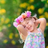 süßes Mädchen mit Blume Stirnband lächelnd im Freien
