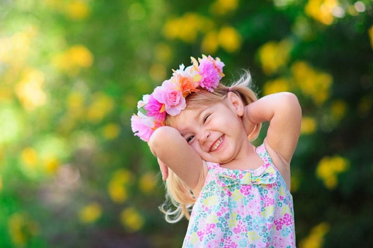 süßes Mädchen mit Blume Stirnband lächelnd im Freien