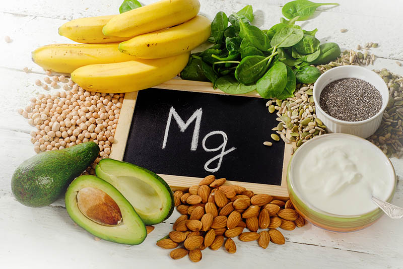 magnesiumhaltige Lebensmittel auf dem Tisch mit Tafel mit Buchstabenzeichen
