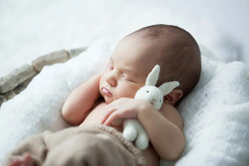 niedlichen Baby Junge schlafen in Umarmung mit Kaninchen Spielzeug