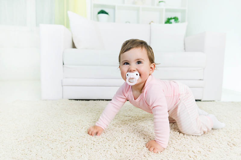 niedlichen Baby Mädchen mit Schnuller auf dem Boden krabbeln