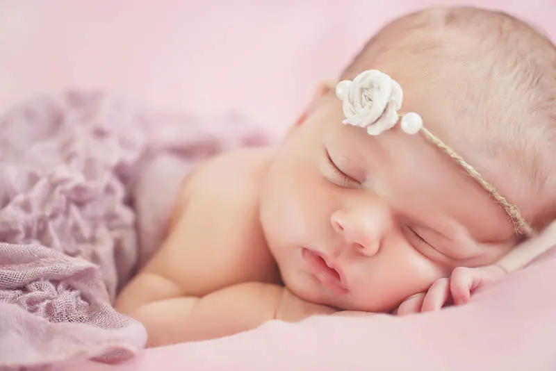 niedlichen Baby Mädchen schlafen mit Blume Stirnband auf dem Kopf