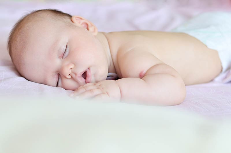niedlichen Baby ohne Shirt schlafen auf dem Bauch mit offenem Mund