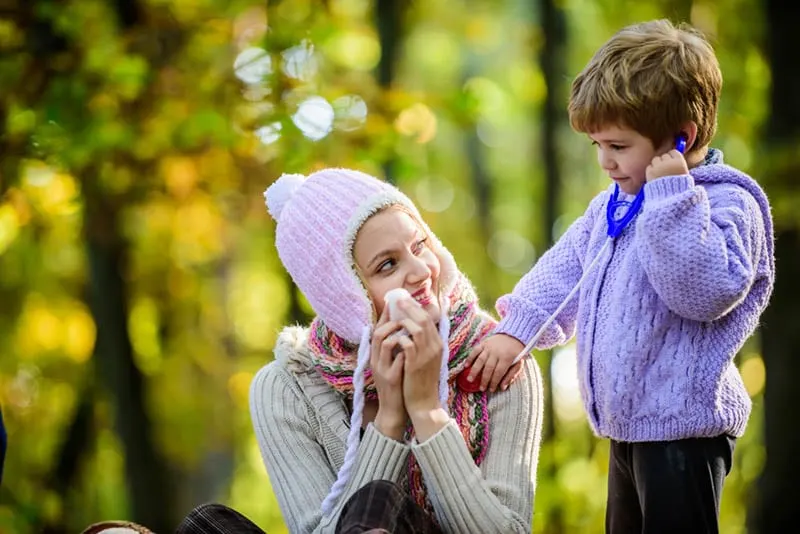 niedlichen kleinen Jungen spielen eine Rolle als Arzt mit seiner Mutter im Freien