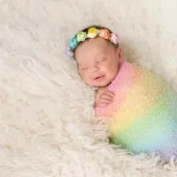 niedlichen Regenbogen Baby lächelnd beim Schlafen in bunte Decke gewickelt
