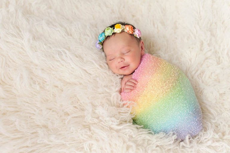 niedlichen Regenbogen Baby lächelnd beim Schlafen in bunte Decke gewickelt