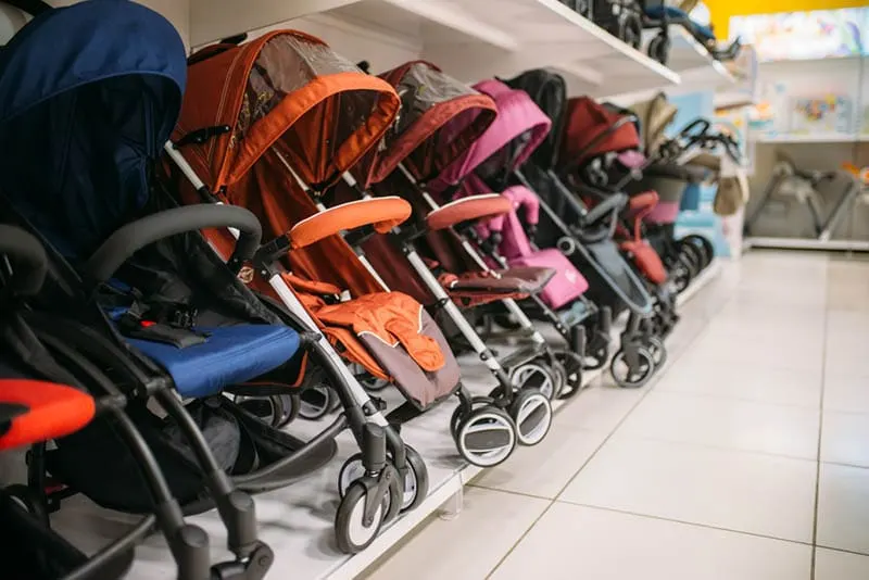 roh von bunten Baby-Kinderwagen auf Regal im Laden