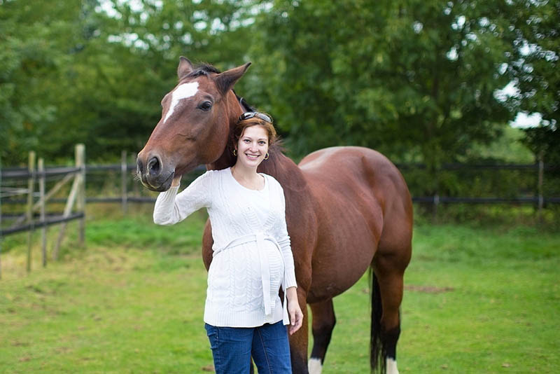 schwangere Frau posiert mit schönen großen Pferd im Freien