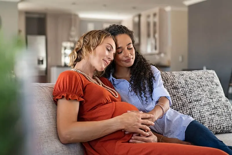 schwangere Frau sitzt auf der Couch mit ihrem Freund Unterstützung