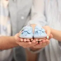 ein Paar hält blaue Babyschuhe