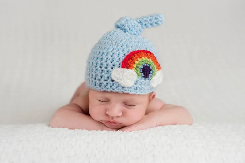 süßes Baby schlafend auf dem Bauch mit Regenbogen Hut