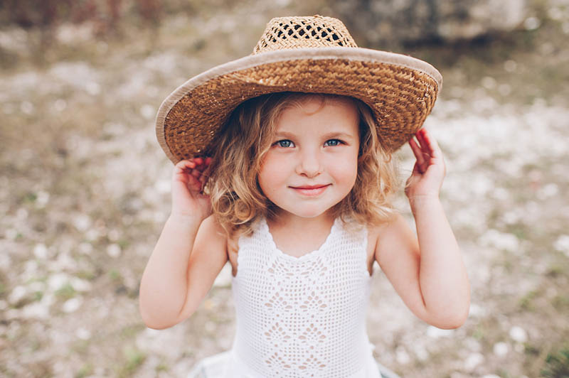 süßes kleines Mädchen posiert mit Hut im Freien