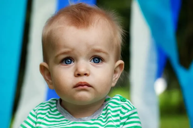 traurig Baby Junge mit großen blauen Augen Blick auf Entfernung im Freien
