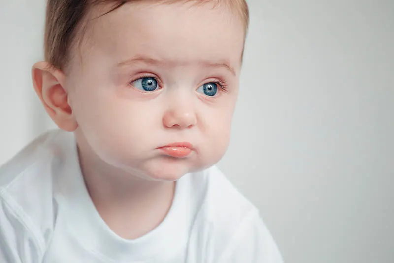 trauriges Baby mit großen blauen Augen schaut in die Ferne