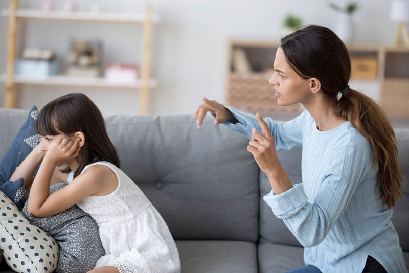 wütende Frau schreit ihre Tochter auf der Couch an