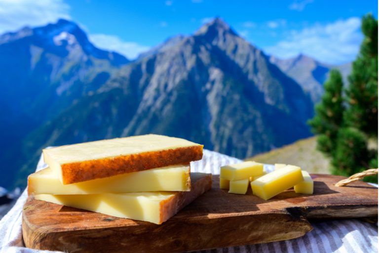 Bergkäse in Scheiben geschnitten und auf einem Holzschneidebrett serviert