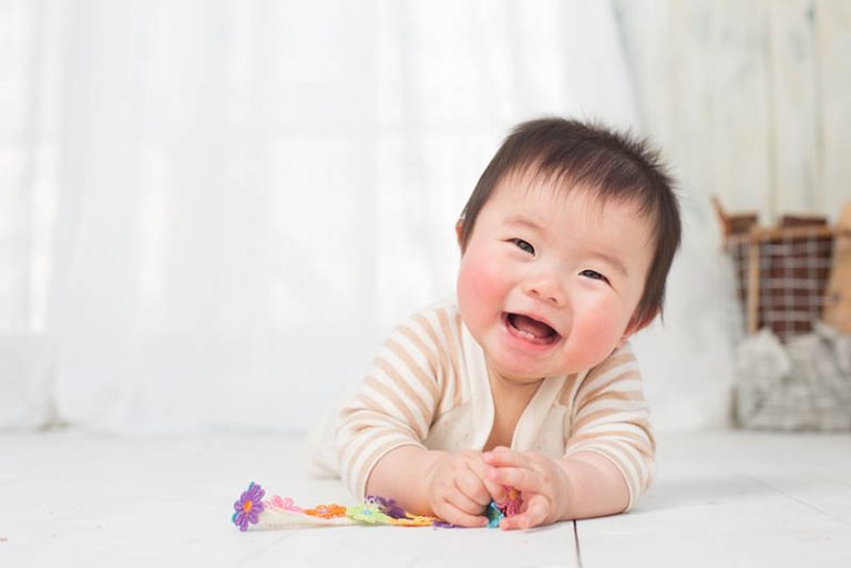 lachendes Baby, das auf dem Boden mit Spielzeug spielt