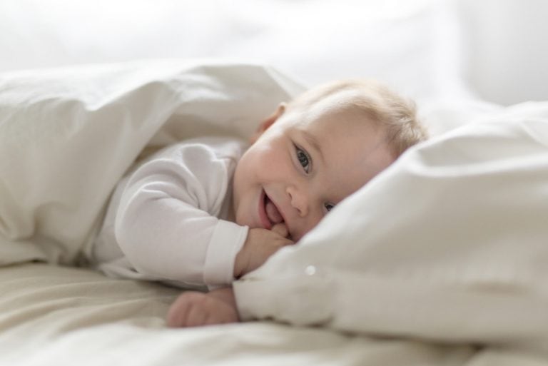 glückliches Baby lächelt und spielt mit seinem Finger