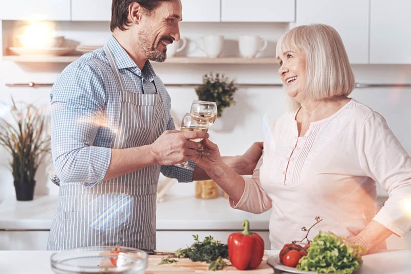 Frau trinkt Weißwein mit ihrem Schwiegersohn in der Küche