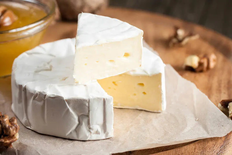 Frischer Brie-Käse und eine Scheibe auf einem Holzbrett mit Nüssen