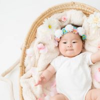 japanische Baby Mädchen liegt in einem Korb mit einer Blume Stirnband