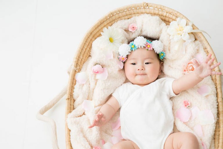 japanische Baby Mädchen liegt in einem Korb mit einer Blume Stirnband