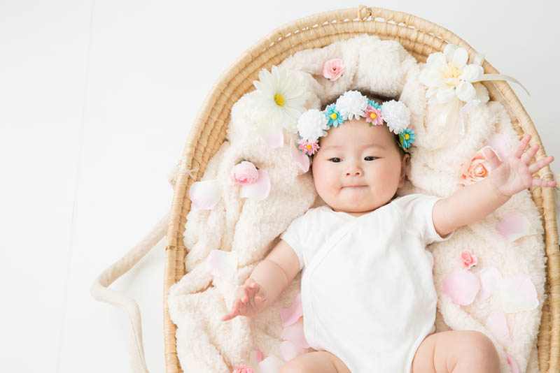 japanische Baby Mädchen liegt in einem Korb mit einer Blume Stirnband