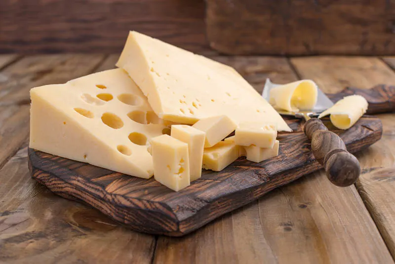 Käse mit Löchern auf dem Holzbrett mit Messer
