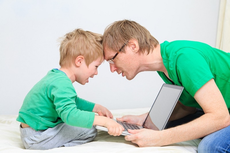 Vater versucht, seinem weinenden Kind den Laptop wegzunehmen