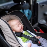 kleines weinendes Baby in einem Autositz mit angelegtem Sicherheitsgurt