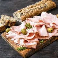 Mortadella in Scheiben geschnitten mit Oliven und Brot auf dem Tisch