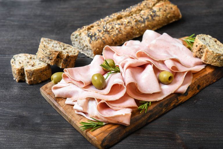 Mortadella in Scheiben geschnitten mit Oliven und Brot auf dem Tisch