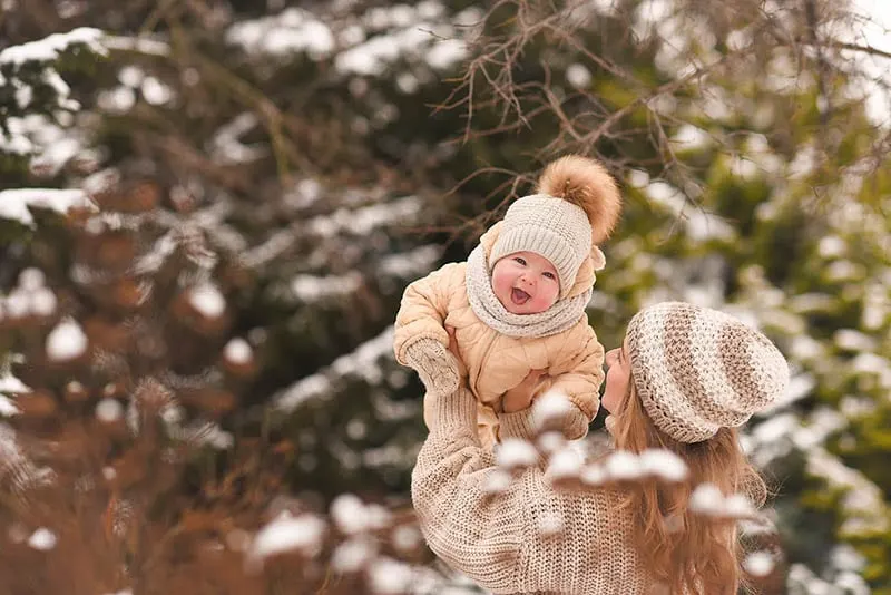 Mutter spielt mit niedlichen Baby Junge auf dem Schnee