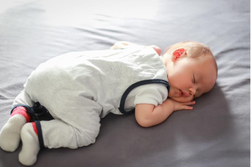 Neugeborener schlafen auf dem Bauch im Bett