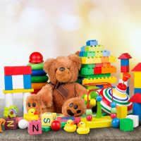 buntes Kinderspielzeug auf dem Holztisch mit Teddybär in der Mitte