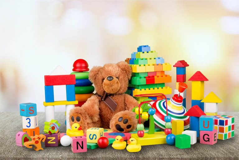 buntes Kinderspielzeug auf dem Holztisch mit Teddybär in der Mitte