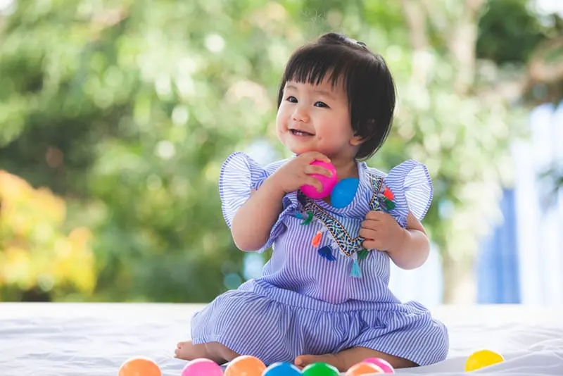 Süßes Baby Mädchen spielt mit bunten Ball Spielzeug
