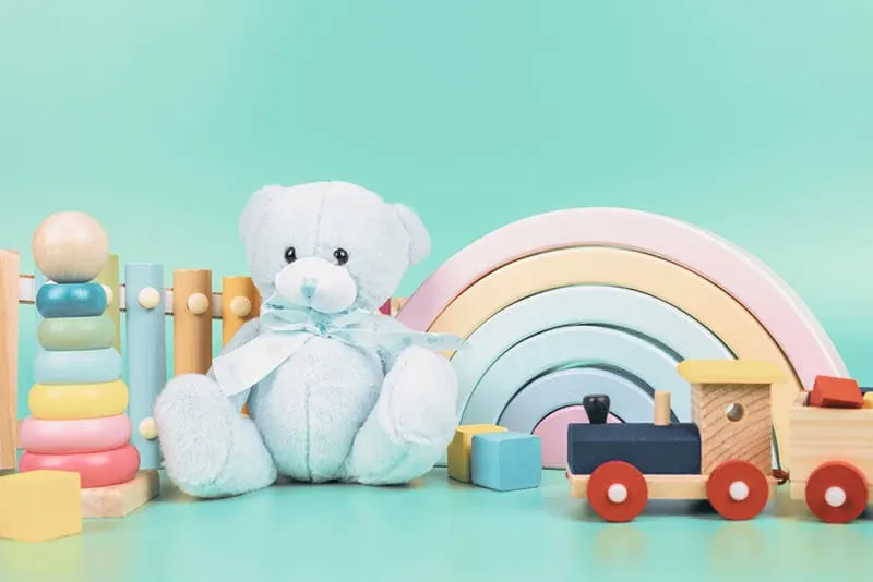 Teddybär, Holz-Regenbogen, Zug und Babyspielzeug auf dem Tisch