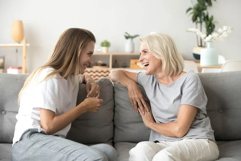 ältere Frau lachend mit ihrer Schwiegertochter auf der Couch