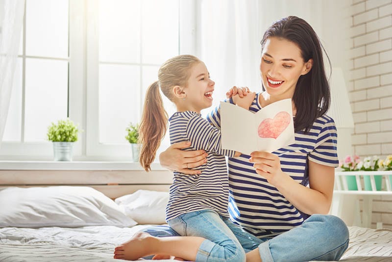 junge Mutter liest Brief von ihrer Tochter auf dem Bett