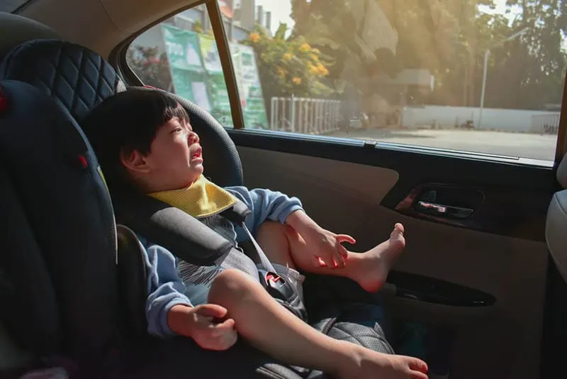 kleiner Junge im Sitz weint während der Fahrt im Auto