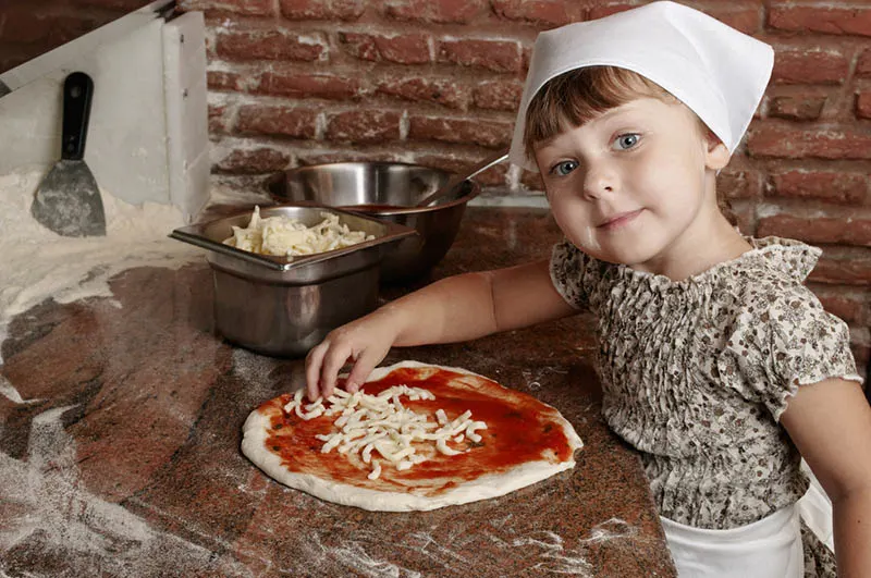 kleines Mädchen macht eine Pizza in der professionellen Küche