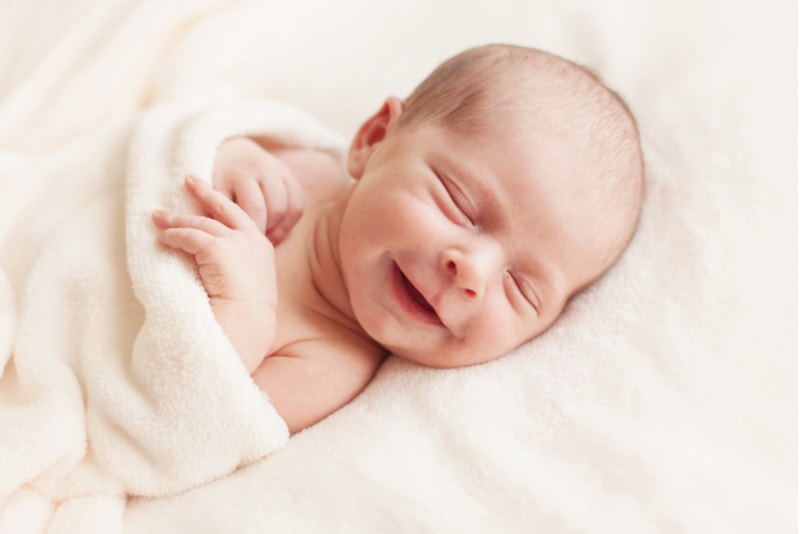 schönes lächelndes Neugeborenes Baby 6 Tage alt