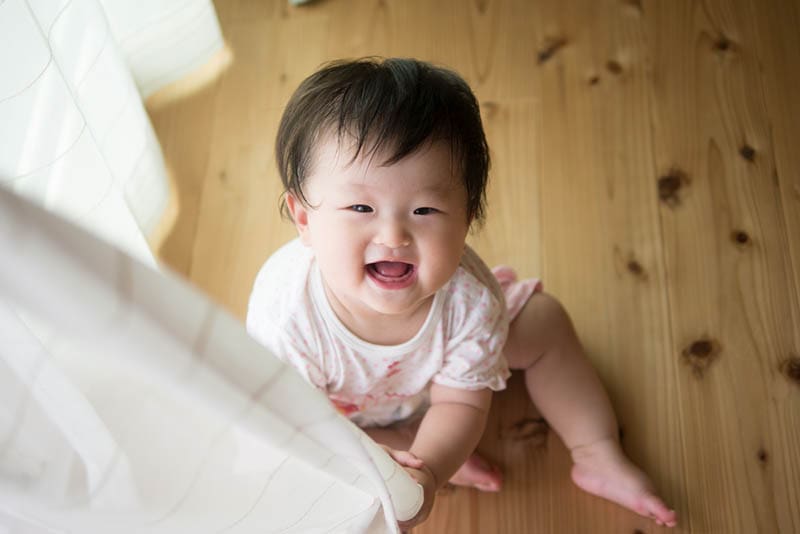 lächelnd Baby Mädchen spielen mit Vorhang