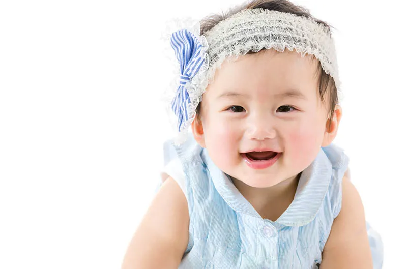 lächelndes Baby Mädchen mit Stirnband krabbelnd
