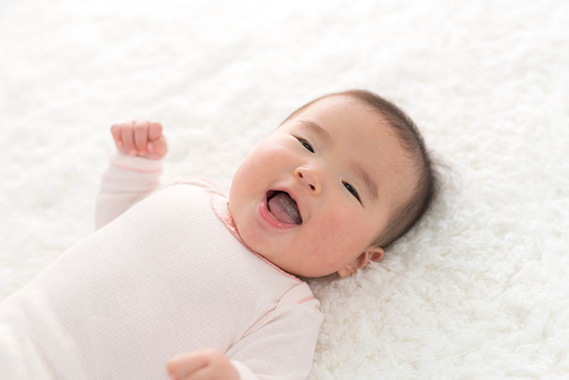lächelndes Baby auf der weißen Matte liegend
