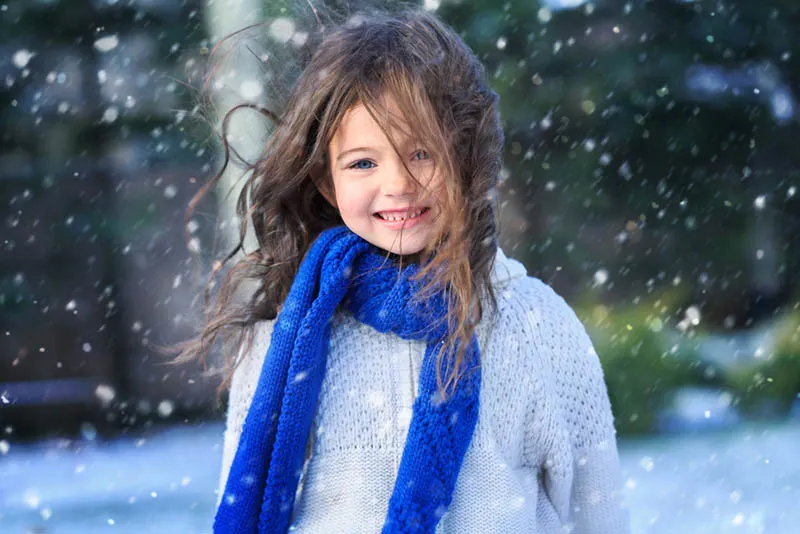 schönes kleines Mädchen auf dem Schnee stehend