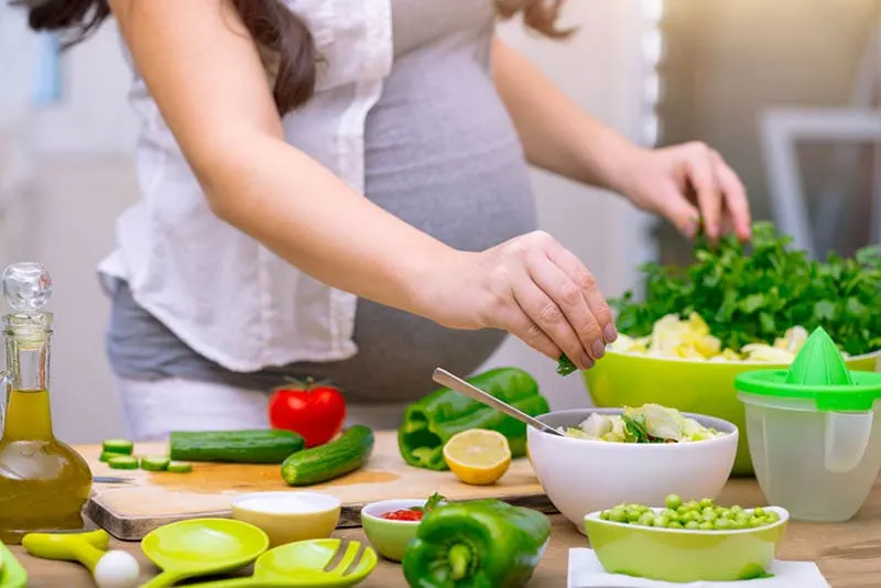 schwangere Frau bei der Zubereitung einer gesunden Mahlzeit aus Gemüse