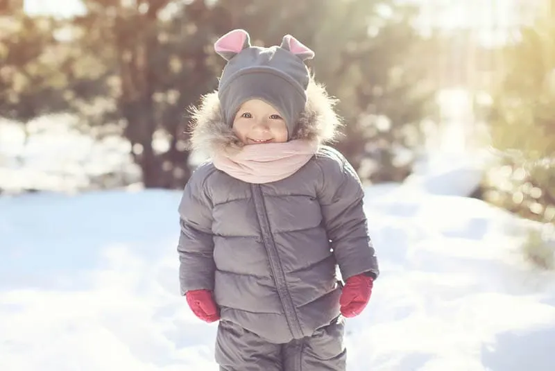 süßer kleiner Junge steht auf dem Schnee