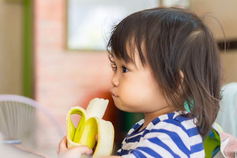süßes Baby Mädchen essen eine Banane